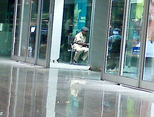 A security guard at Bangalore International Airport preparing tobacco instead of gaurading airport entrance